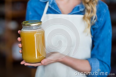 Mid-section of female staff holding jar of honey Stock Photo