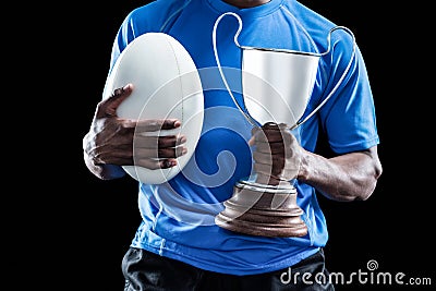 Mid section of sportsman holding trophy and rugby ball Stock Photo