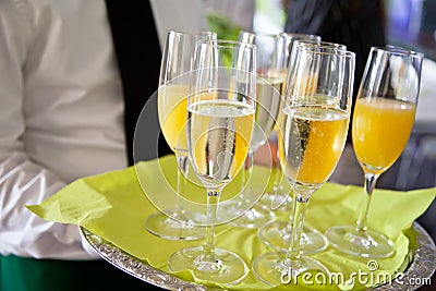 Mid section view of waiter serving champagne and orange juice on Stock Photo