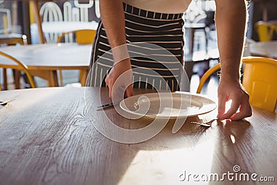 Mid section of waiter arranging plate on table Stock Photo