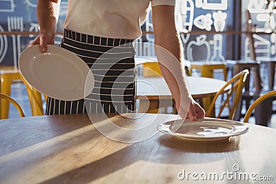 Mid section of waiter arranging plates on table Stock Photo