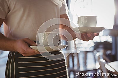 Mid section of waiter holding coffee cups in cafe Stock Photo