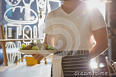 Mid section of waiter holding plate with salad in cafe Stock Photo