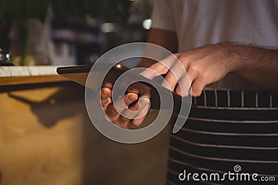 Mid section of waiter using tablet by counter Stock Photo