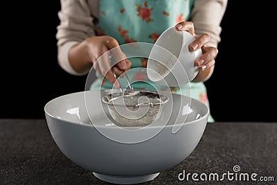 Woman sieving flour into the bowl Stock Photo