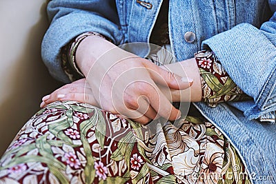 Mid section of young woman wearing denim jacket over summer dress with floral pattern Stock Photo