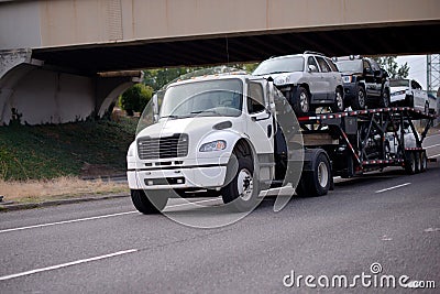 Mid size semi truck car hauler transporting vehicles on the road Stock Photo