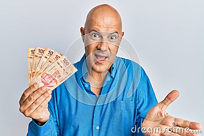 Middle age bald man holding mexican pesos celebrating achievement with happy smile and winner expression with raised hand Stock Photo