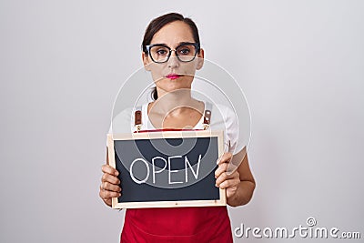 Middle age brunette woman holding banner with open text thinking attitude and sober expression looking self confident Stock Photo