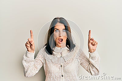 Middle age brunette woman pointing up with fingers afraid and shocked with surprise and amazed expression, fear and excited face Stock Photo