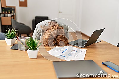 Middle age businesswoman overworked with head on desk at the office Stock Photo