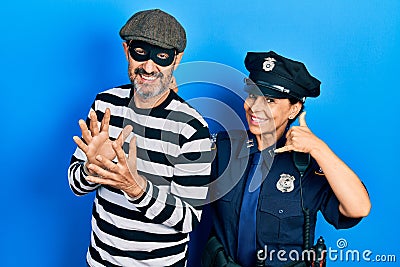 Middle age couple of hispanic woman and man wearing thief and police uniform smiling doing phone gesture with hand and fingers Stock Photo