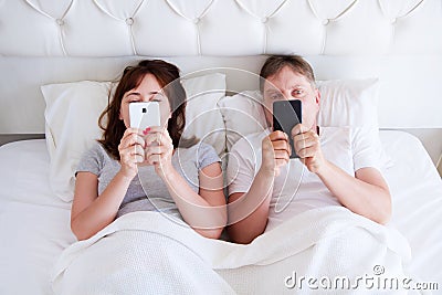 Middle age couple hold cell phones in bedroom, modern family Stock Photo