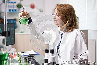 Middle age female biologist in a laboratory looking at chemical test tube Stock Photo