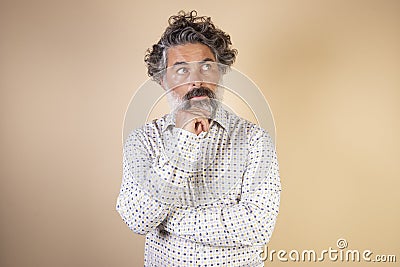 Middle age grey-haired man in casual clothes with hand on chin thinking about question, expression of penitence. doubt concept Stock Photo