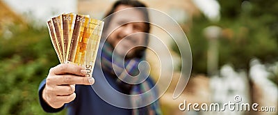 Middle age handsome man holding norwegian krone banknotes outdoors at the park Stock Photo