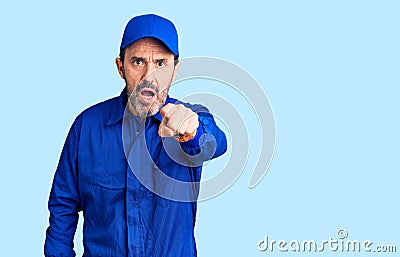 Middle age handsome man wearing mechanic uniform pointing displeased and frustrated to the camera, angry and furious with you Stock Photo