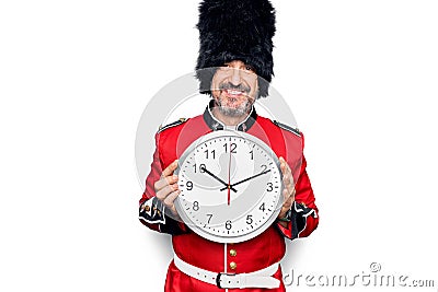 Middle age handsome wales guard man wearing traditional uniform holding big clock looking positive and happy standing and smiling Stock Photo