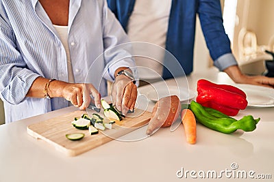 Middle age hispanic couple cutting zucchini at kitchen Stock Photo