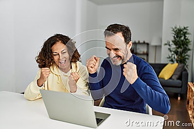 Middle age hispanic couple smiling happy with fists raised up Stock Photo