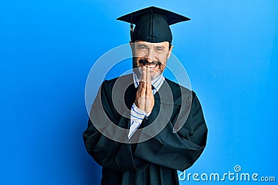 Middle age hispanic man wearing graduation cap and ceremony robe praying with hands together asking for forgiveness smiling Stock Photo