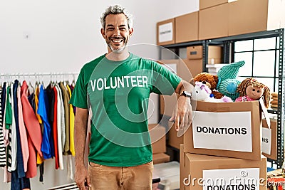 Middle age hispanic man wearing volunteer t shirt at donations stand with a happy and cool smile on face Stock Photo