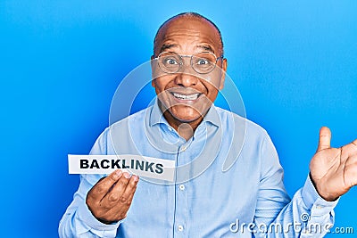 Middle age latin man holding paper with backlinks message celebrating victory with happy smile and winner expression with raised Stock Photo