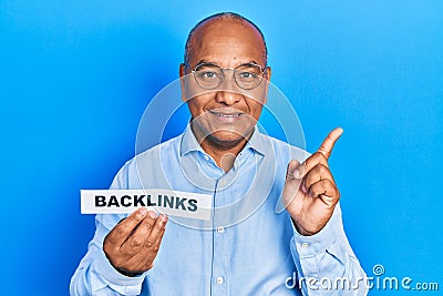 Middle age latin man holding paper with backlinks message smiling happy pointing with hand and finger to the side Stock Photo