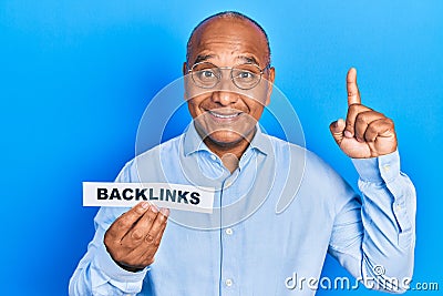 Middle age latin man holding paper with backlinks message surprised with an idea or question pointing finger with happy face, Stock Photo