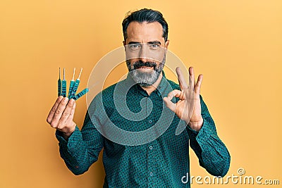 Middle age man with beard and grey hair holding picklock to unlock security door doing ok sign with fingers, smiling friendly Stock Photo