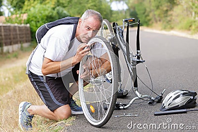 Middle-age man fixing bike outdoors Stock Photo