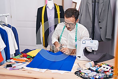 Middle age man tailor cutting cloth at tailor shop Stock Photo