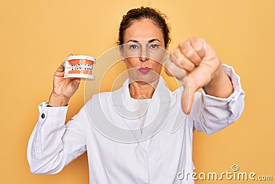 Middle age senior dentist woman holding orthodontics denture with braces aligner with angry face, negative sign showing dislike Stock Photo