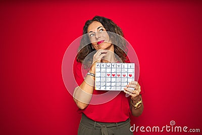 Middle age senior woman holding menstruation calendar over red isolated background serious face thinking about question, very Stock Photo