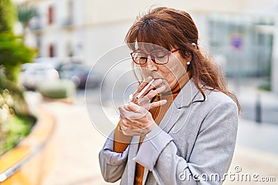 Middle age woman business executive smoking cigarette at park Stock Photo