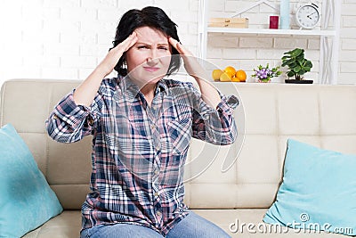 Middle age Woman suffering from a headache and stress holding her hands to her temples with her eyes opened in pain Stock Photo