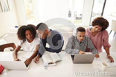 Middle aged African American parents helping their teenage kids using laptops to do homework, elevated view Stock Photo