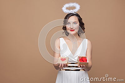 Middle aged angel woman in white dress and nimbus holding gift b Stock Photo