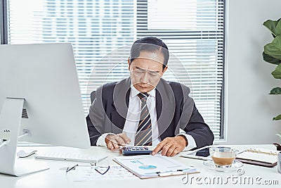 Middle aged Asian businessman feeling stressed and frustrated while working in work station. Business problem concept Stock Photo
