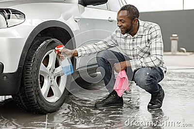 Middle aged black man with a sprayer bottle for polishing car in the car wash Stock Photo