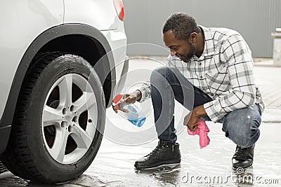 Middle aged black man with a sprayer bottle for polishing car in the car wash Stock Photo