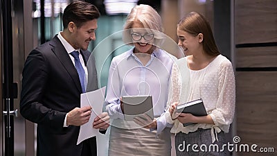 Mature boss and subordinates talking standing in office hallway Stock Photo