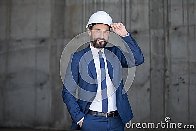 Middle aged businessman in hard hat and suit standing and smiling at work Stock Photo