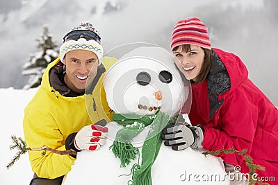 Middle Aged Couple Building Snowman On Ski Holiday Stock Photo