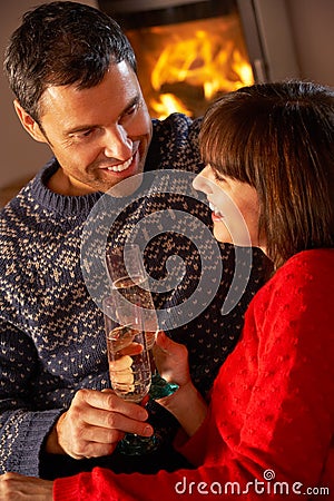 Middle Aged Couple Sitting Sofa By Cosy Log Fire Stock Photo