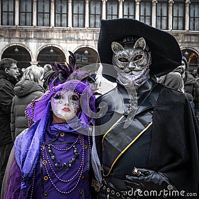 Middle aged couple - woman in purple carnival suit, man in Puss in Boots suit - at carnival in Venice, Italy Editorial Stock Photo