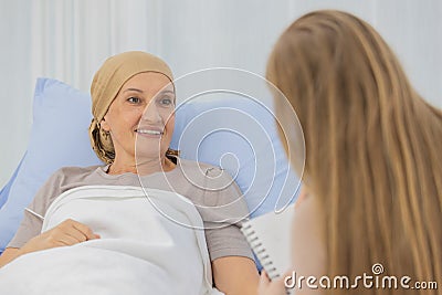 A middle-aged end-state breast cancer patient lay on the bed and tells her life`s story for a ghostwriter to write her biography Stock Photo