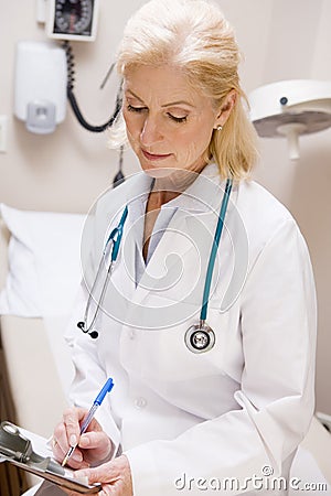 Middle Aged Female Doctor Writing On A Clipboard Stock Photo