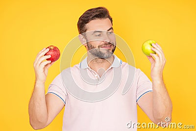 Middle aged happy smiling man bitting apple, healthy lifestyle. Man holds a fresh green apple studio portrait on yellow Stock Photo