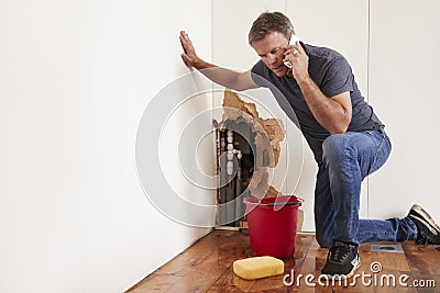 Middle aged man with a burst water pipe phoning for help Stock Photo